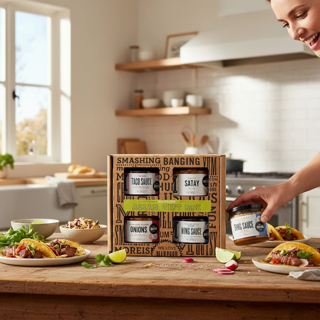 Manfood Cambs Asian gift box featuring four jars of gourmet sauces and pickles on a kitchen table with tacos.