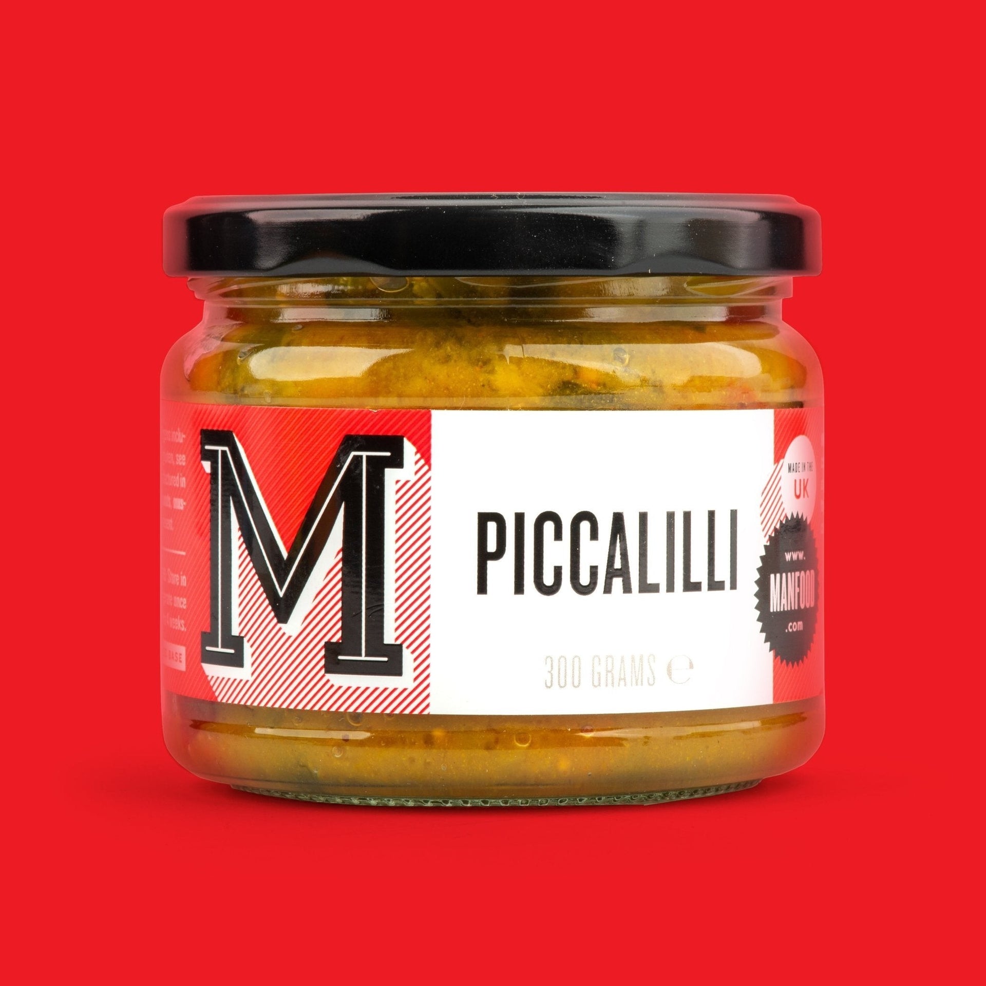 Manfood chunky piccalilli in a glass jar with a white label against a vibrant red background.