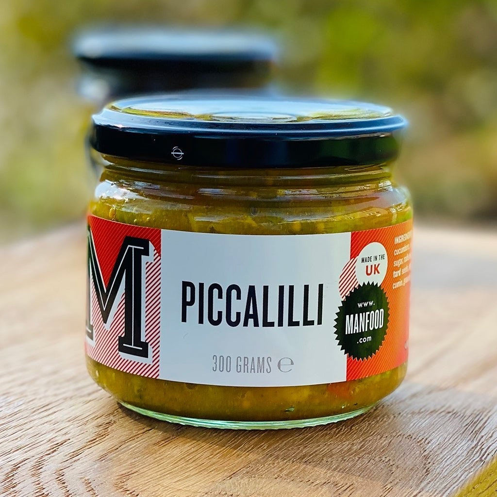 Manfood chunky piccalilli in a glass jar with a black lid, featuring a vibrant mustard sauce and vegetables.