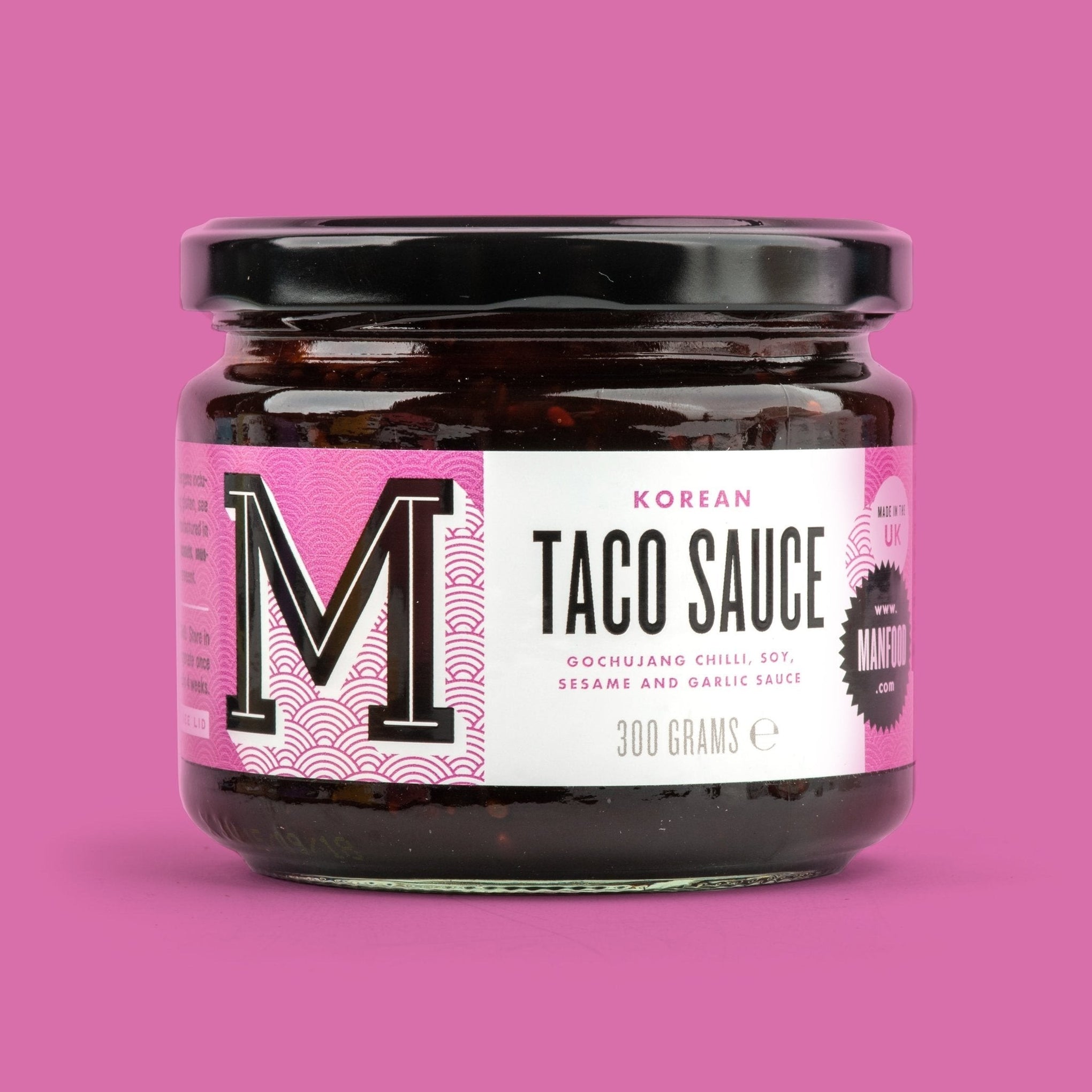Manfood Korean Taco Sauce in a glass jar with a pink label featuring gochujang, soy, sesame, and garlic.