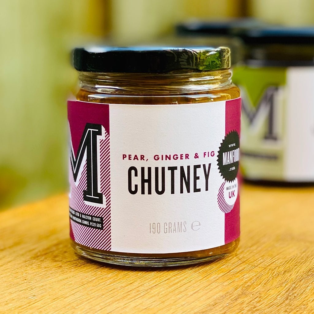 Manfood pear, ginger, and fig chutney in a glass jar on a wooden surface.