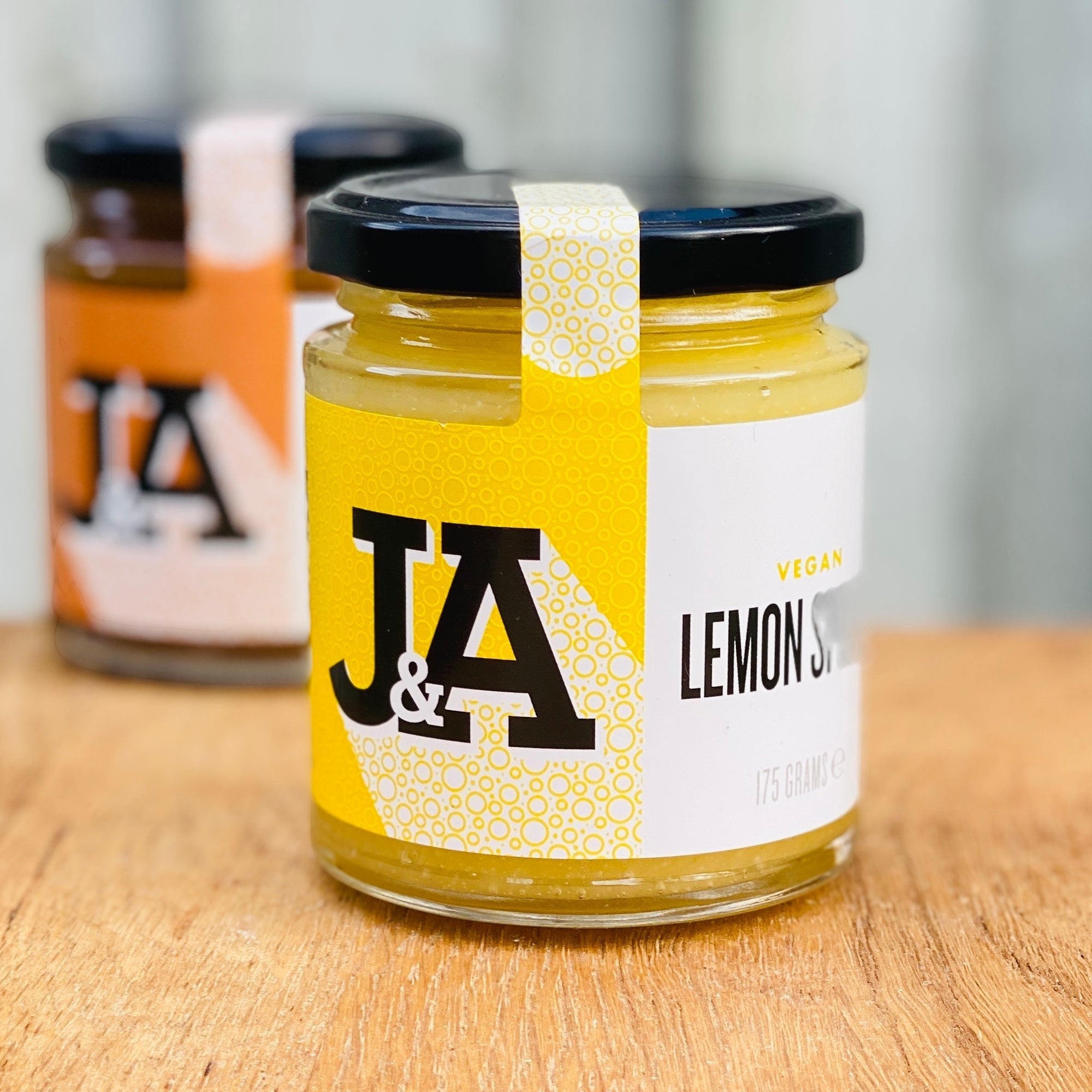 Manfood vegan lemon curd in a 175g glass jar with a yellow and white label on a wooden surface