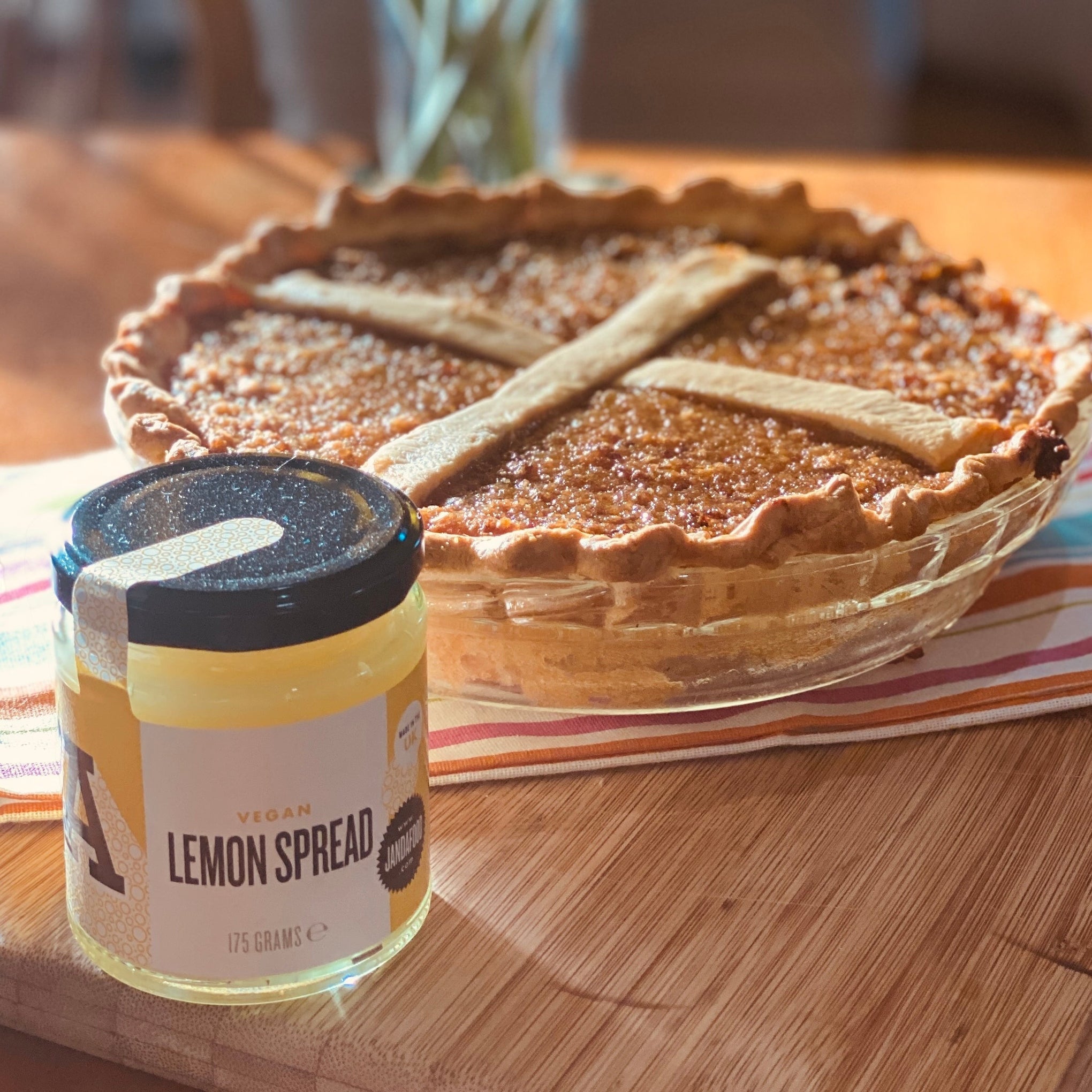 Manfood vegan lemon spread jar next to a baked pie on a wooden table